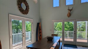 Un vaste espace dédié à la salle à manger, avec une grande table et des chaises en bois, une guirlande décorative accrochée au mur et une tête de cerf fixée au mur.