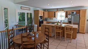 Une cuisine spacieuse dotée de meubles en bois, d’un îlot central et d’un coin repas avec une table ronde et des chaises.