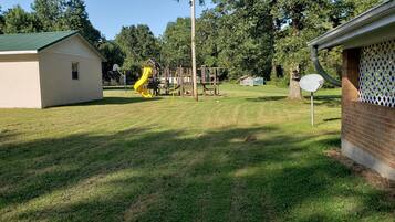Enjoy a family-friendly atmosphere in this backyard with a lawn, play structures, and a playhouse.