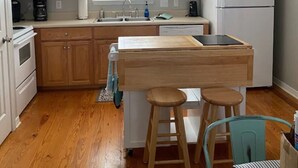 Una cocina compacta con armarios de madera, una isla integrada, un refrigerador y un comedor con taburetes.