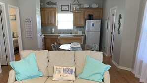 Una sala de estar con un sofá color beige, dos almohadas azul claro y una alfombra tejida.