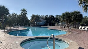 Una piscina con hidromasaje, rodeada de palmeras y sillas de descanso.