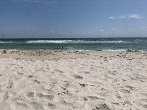 Ein Sandstrand mit Fußspuren und einer Person, die im Wasser schwimmt.