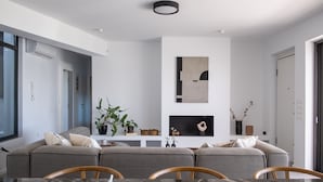 Un salon moderne comprenant un ensemble de canapés, une table à manger avec des chaises et un coin cuisine doté d’un plan de travail en marbre.