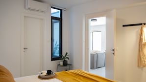 Une chambre à coucher avec un lit, une table de chevet avec une lampe, une fenêtre et une porte donnant sur une autre pièce.