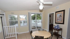 A dining area with a round table, chairs, a ceiling fan, and a view of the outdoors through large windows. - Silver Sands, Oceanfront - Gulf Beach Resort (Longboat Key)