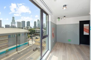 Een modern hotelinterieur met grote ramen met uitzicht over de stad, een schone vloer en een vluchtwegbord op de muur.