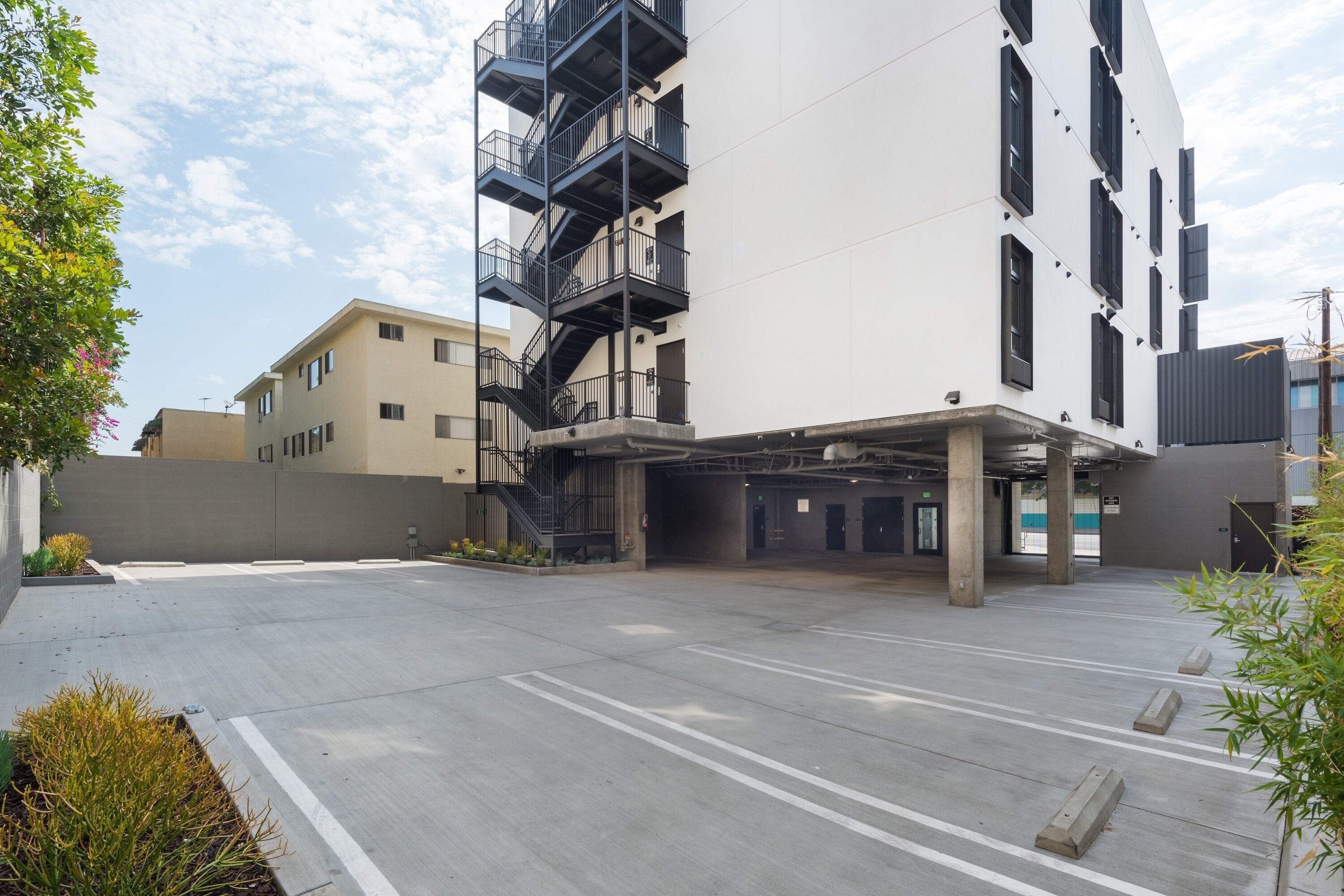 A modern building with a parking area, a staircase, and a flat entrance.