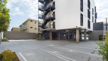 A modern building with a parking area, a staircase, and a flat entrance.
