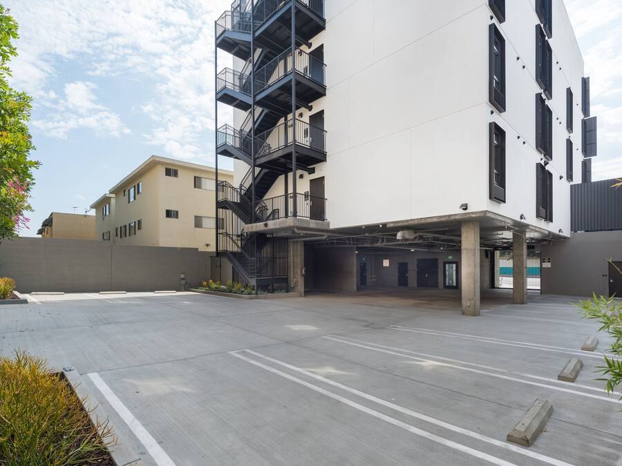 Um edifício moderno com área de estacionamento, escadas e entrada plana.