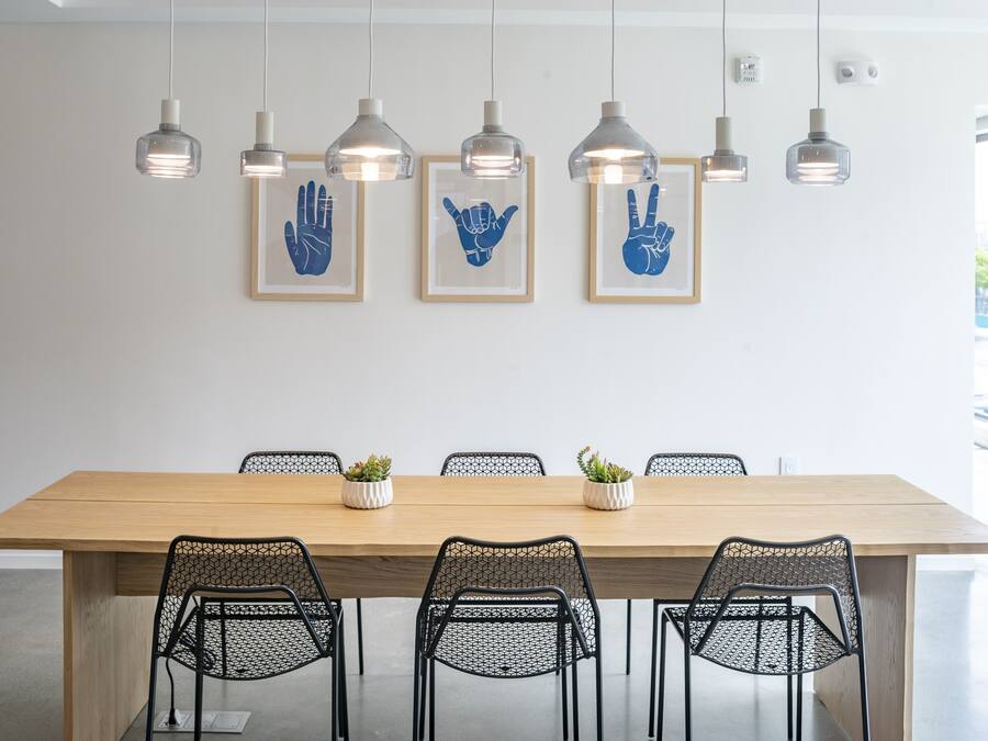 A modern dining area with a wooden table, black mesh chairs, and pendant lights.