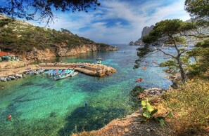 A coastal scene with clear waters, boats, and a rocky landscape.