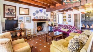 Un saló d'estar acollidor amb una llar de foc, coixins estampats i una televisió.