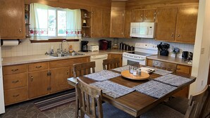 Una cocina con armarios de madera, microondas, estufa y una mesa de comedor con sillas.
