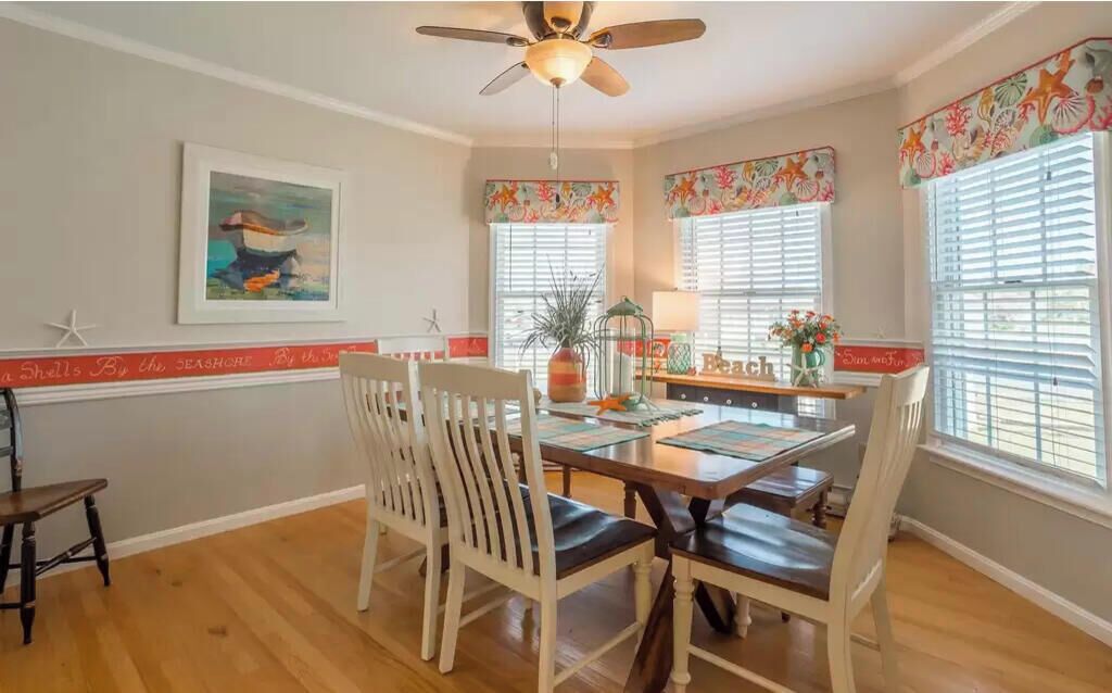 A dining area with a wooden table, white chairs, and a ceiling fan.