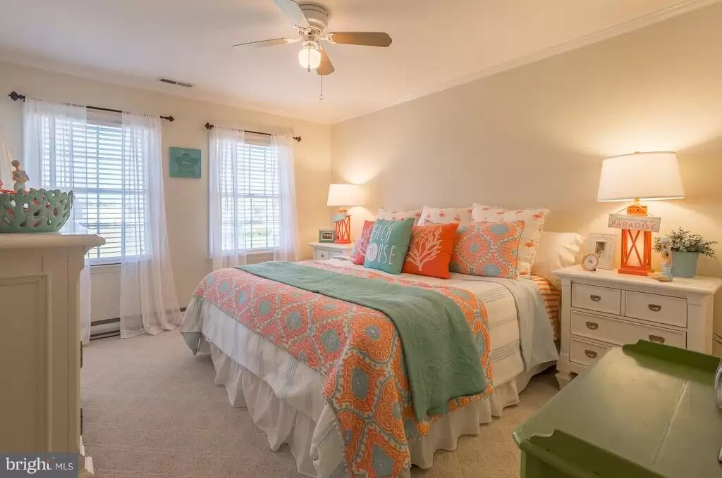 A bedroom with a bed, nightstands, a lamp, a ceiling fan, and a window with curtains.