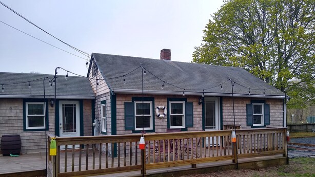 Een houten gebouw met een veranda, een klein terras en een omheind gebied.