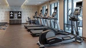 Ein Fitnessstudio mit Laufbändern, Crosstrainern und Gewichten.