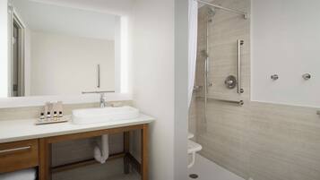 A modern bathroom with a white sink, wooden vanity, and a shower with a glass door.