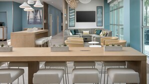A modern hotel lobby with a long reception desk, seating area, and large windows. - Element by Marriott Jacksonville Beach (Jacksonville Beach)
