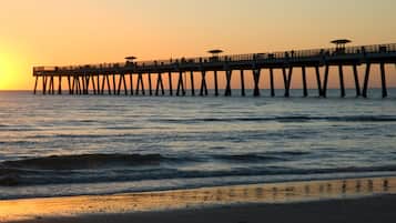 A pier extending into the water with a sunset in the background.