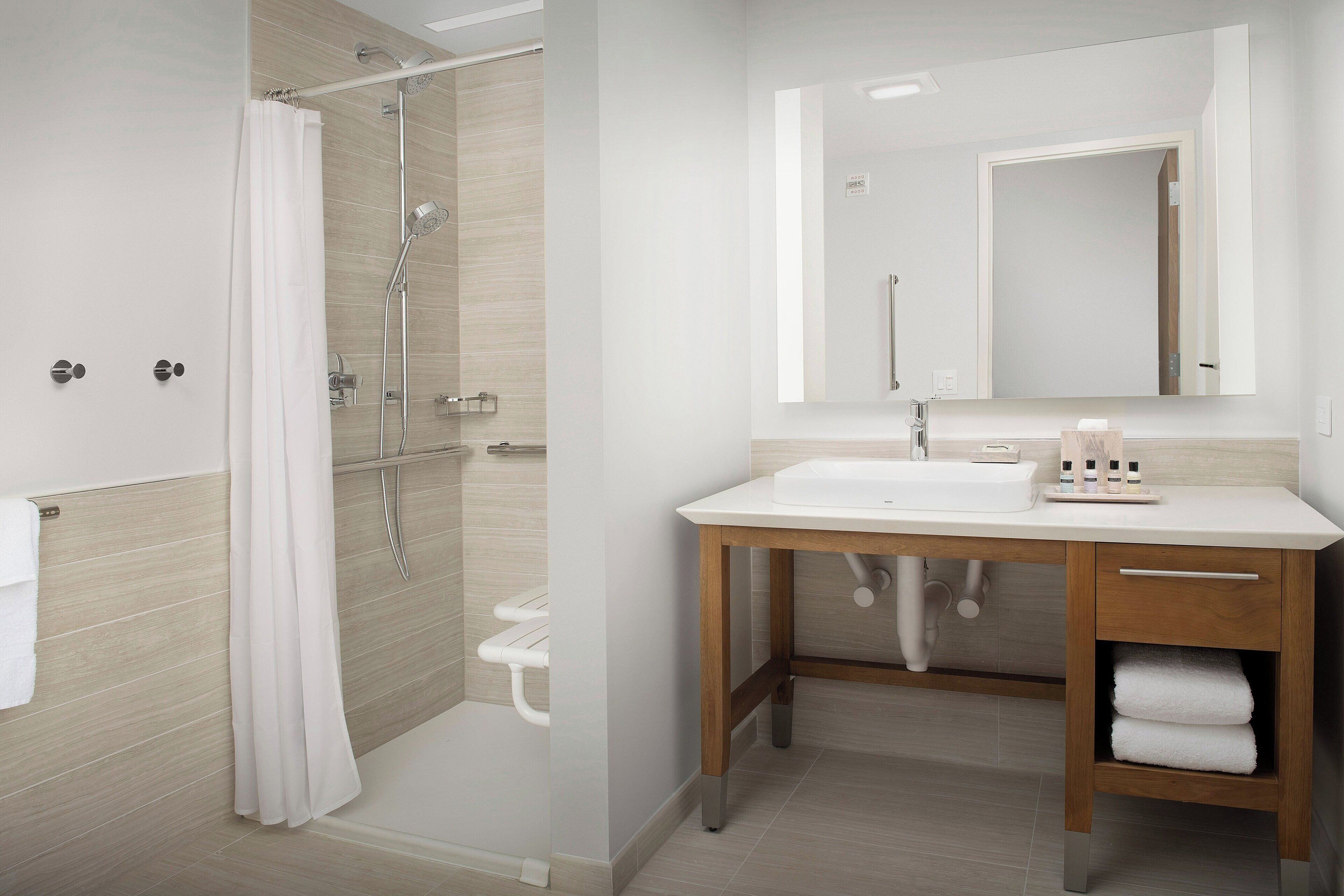 Une salle de bain moderne avec une douche, un lavabo et un miroir.