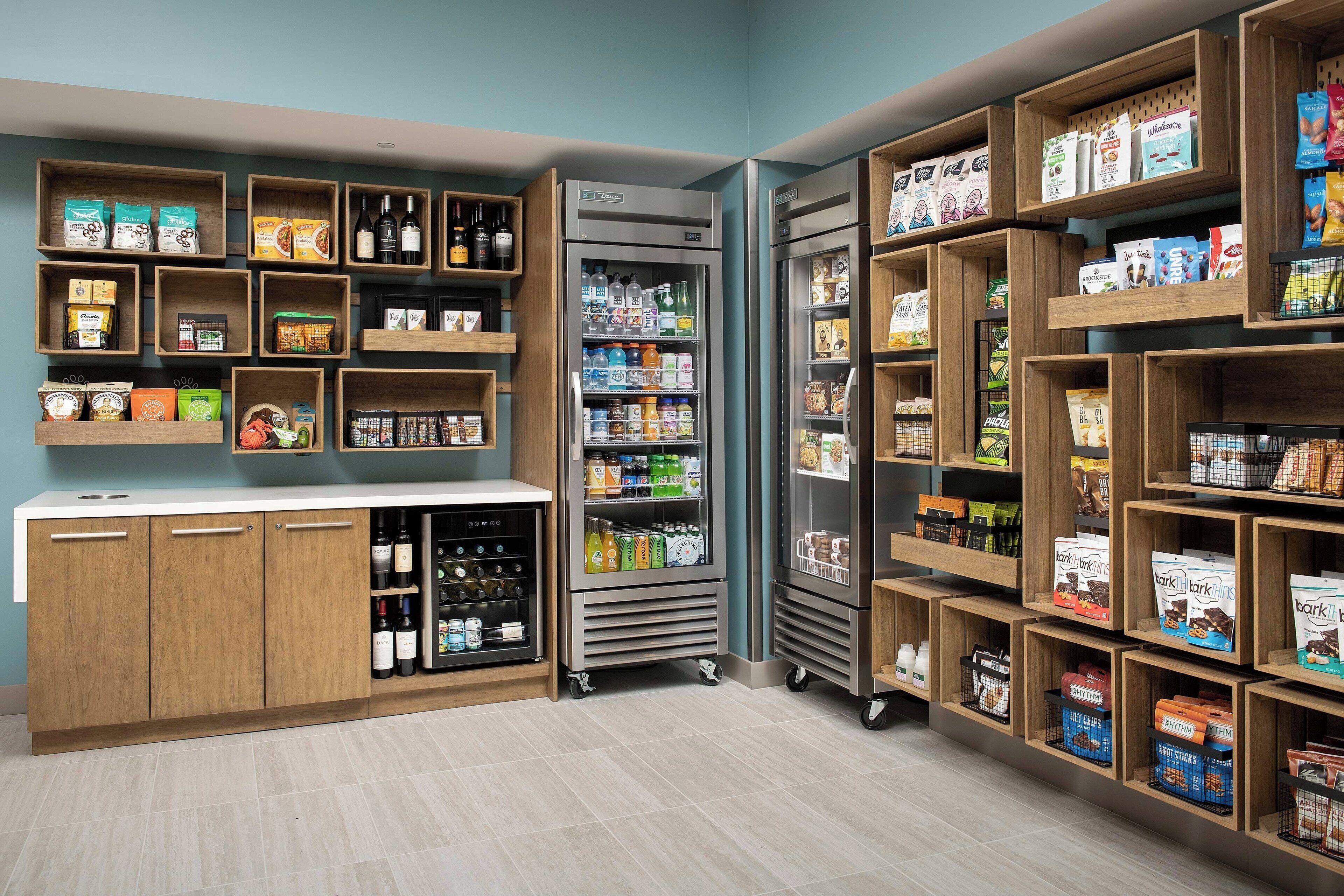 Een overzichtelijke winkel met schappen vol diverse producten, een koelgedeelte en een toonbank met een vitrine.