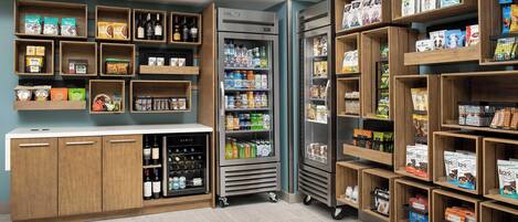 A well-organized store with shelves stocked with various products, a refrigerated section, and a counter with a display case.