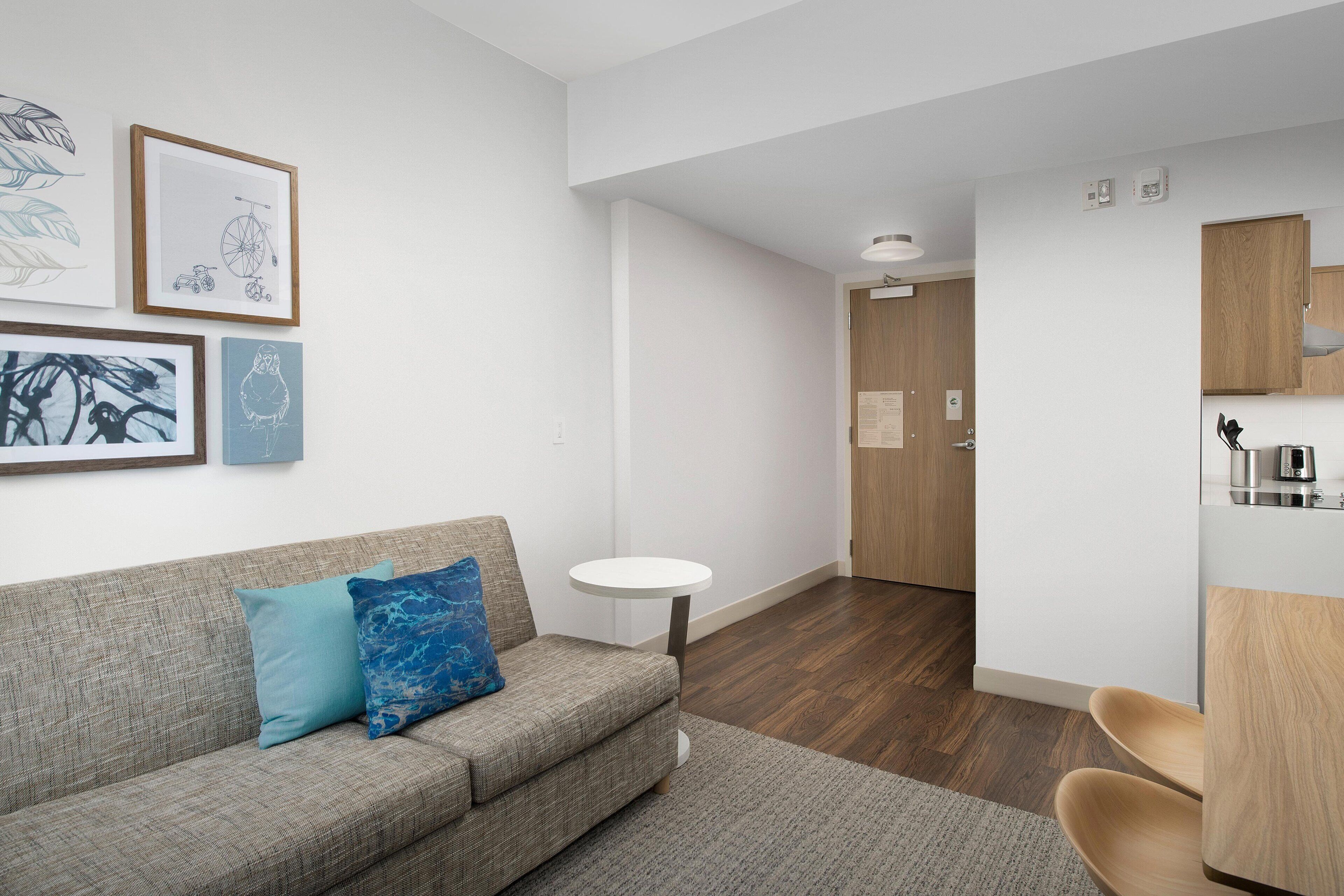 Una sala moderna con un sofá gris, una mesita redonda blanca y cuadros en la pared.