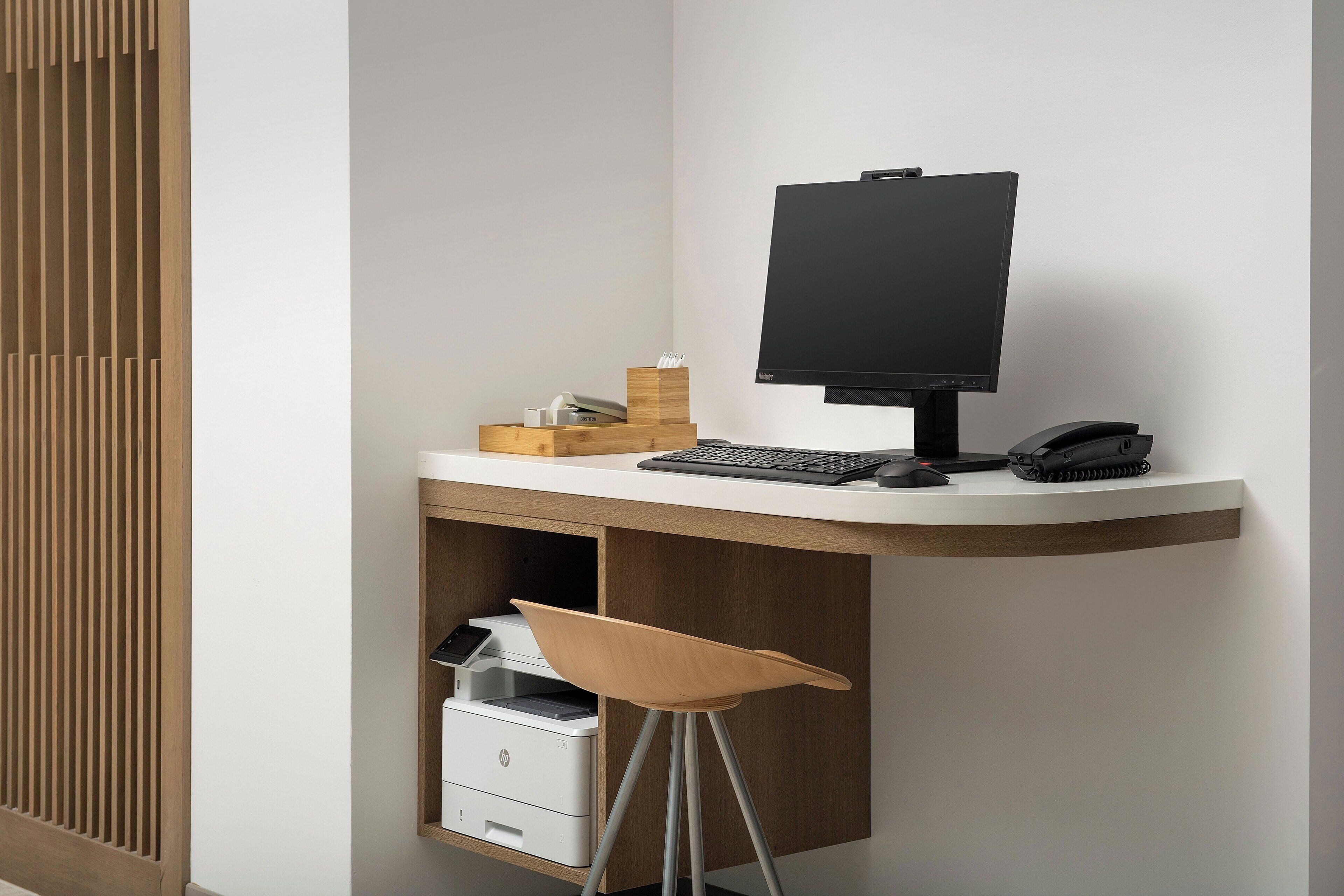 Een modern bureau met een computer, toetsenbord en muis. Een printer en een stoel staan ervoor.