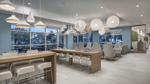 A modern conference room with a long table, several chairs, and pendant lighting. - Element by Marriott Jacksonville Beach (Jacksonville Beach)