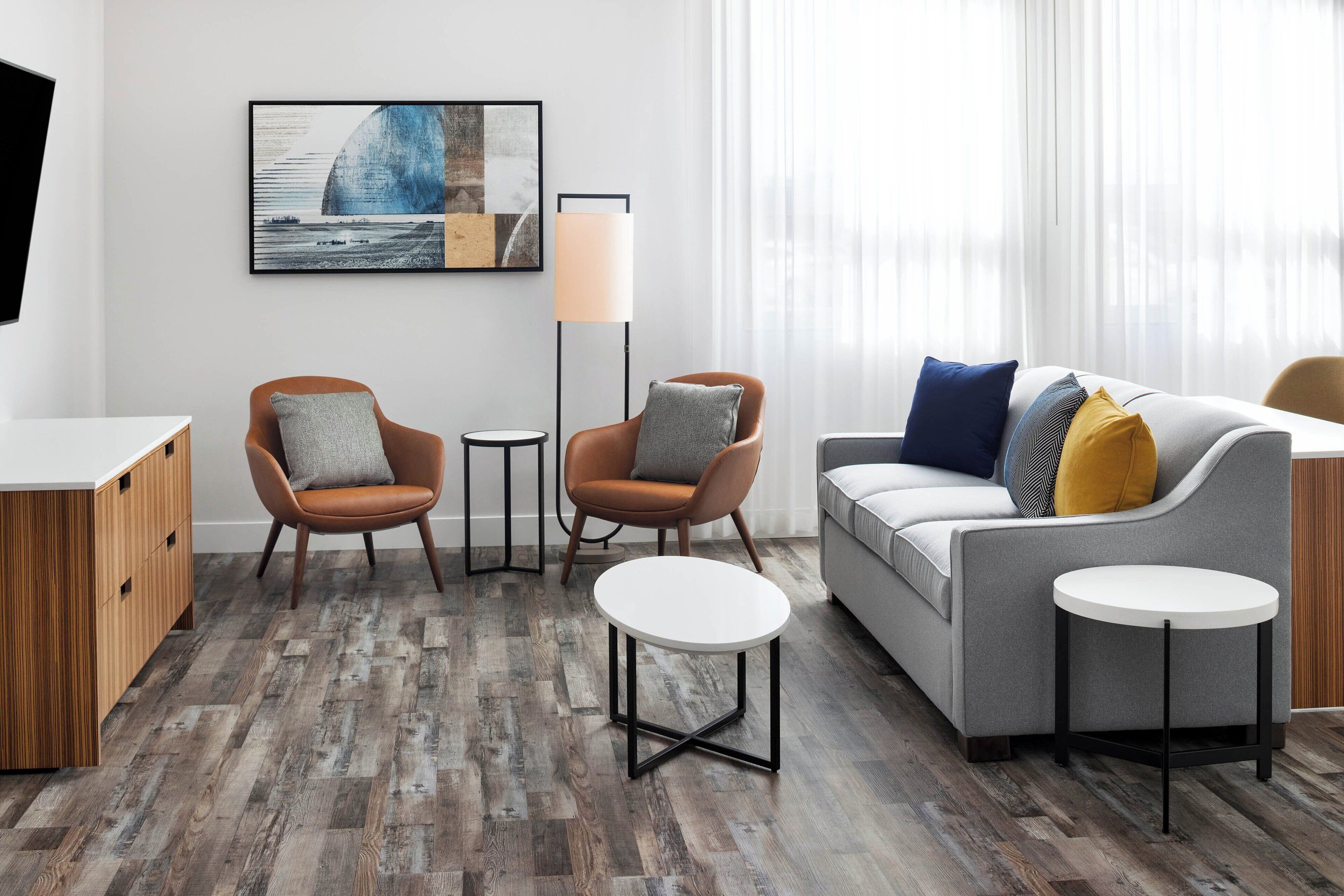 A modern living room with a grey sofa, two armchairs, a coffee table, and a floor lamp.