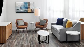 A modern living room with a grey sofa, two armchairs, a coffee table, and a floor lamp.