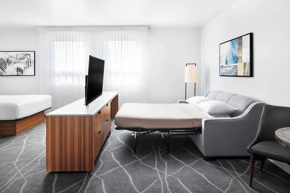 Une chambre d’hôtel avec un lit, un canapé, une télévision, un bureau et une lampe.