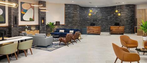 A spacious living area with a stone wall, modern furniture, and pendant lighting.