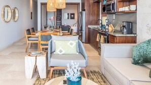 Ein modernes Wohnzimmer mit Sofa, Esstisch und Küchenzeile mit Holzschränken und Geräten.