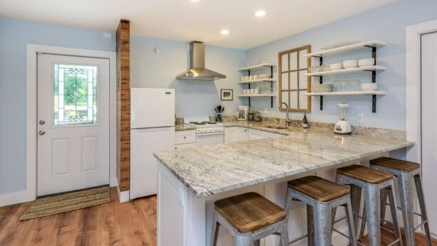 A modern kitchen with a marble countertop, wooden stools, and built-in shelves. - Main-Stay is a larger 2/1 central to all Naples (Naples)