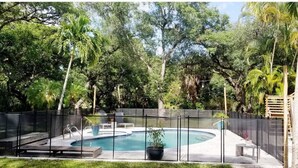 A backyard with a swimming pool, surrounded by a fence, and various plants and trees. - Main-Stay is a larger 2/1 central to all Naples (Naples)