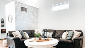 Ein Wohnzimmer mit zwei dunkelbraunen Ledersofas, einem weißen Couchtisch und einem gemusterten Teppich.