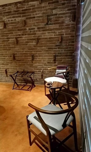Two comfortable chairs face each other in this cozy space, surrounded by a rustic brick wall and polished concrete floor.