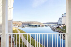 A view from a balcony overlooking a marina with boats, a dock, and a building with a flat roof.