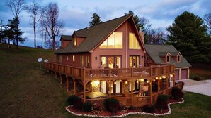 A large, multi-story wooden house with a balcony and a stone foundation. - Luxury Mountain Lodge: Hot Tub and Incredible Mountain Views (Vesuvius)