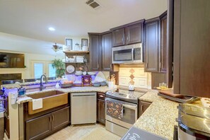 A modern kitchen with dark wood cabinets, stainless steel appliances, and a granite countertop. - Family-Friendly Home w/ Lake Oconee Access + Patio (Eatonton)