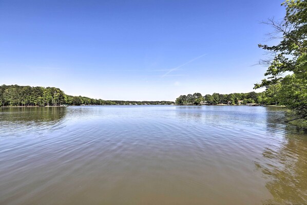 A calm lake with a clear sky, surrounded by dense trees and a distant bridge. - Family-Friendly Home w/ Lake Oconee Access + Patio (Eatonton)