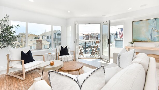 Ein geräumiges Wohnzimmer mit großem Fenster, einem Balkon und Blick auf die Nachbarschaft.