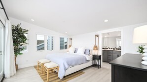 Ein modernes Schlafzimmer mit Bett, Nachttischen, einem großen Fenster und Blick ins Freie.