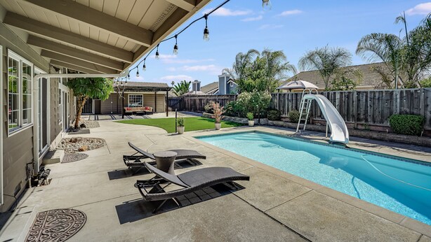 A backyard with a swimming pool, lounge chairs, a slide, and string lights. - POOL. Spacious 4BR/2B. SF Bay Area (Newark)