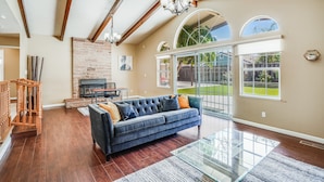 A spacious living room with a large dark blue sofa, a glass coffee table, and a fireplace. - POOL. Spacious 4BR/2B. SF Bay Area (Newark)