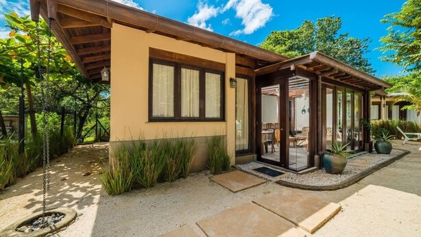 Ein modernes Haus mit überdachter Veranda, Kiesweg und Kübelpflanzen.