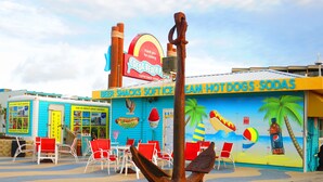 A colorful building with a sign for 'Cocoa Beach Attractions' and a mural depicting a beach scene. - COCOA BEACH OASIS, STEPS TO THE BEACH, HEATED POOL, GREAT AMENITIES AND LOCATION (Cocoa Beach)